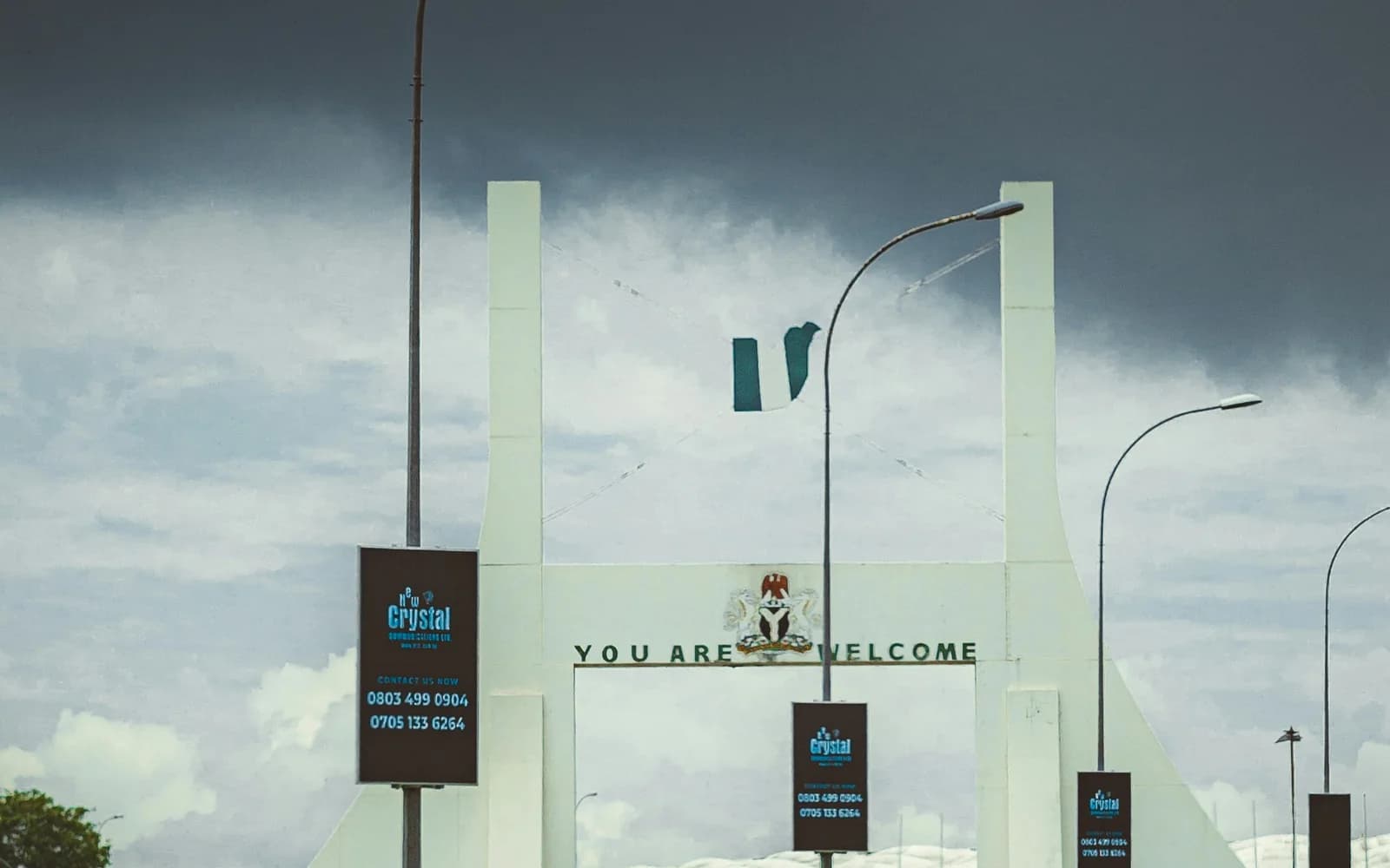 Abuja city gateway beneath a dramatic sky